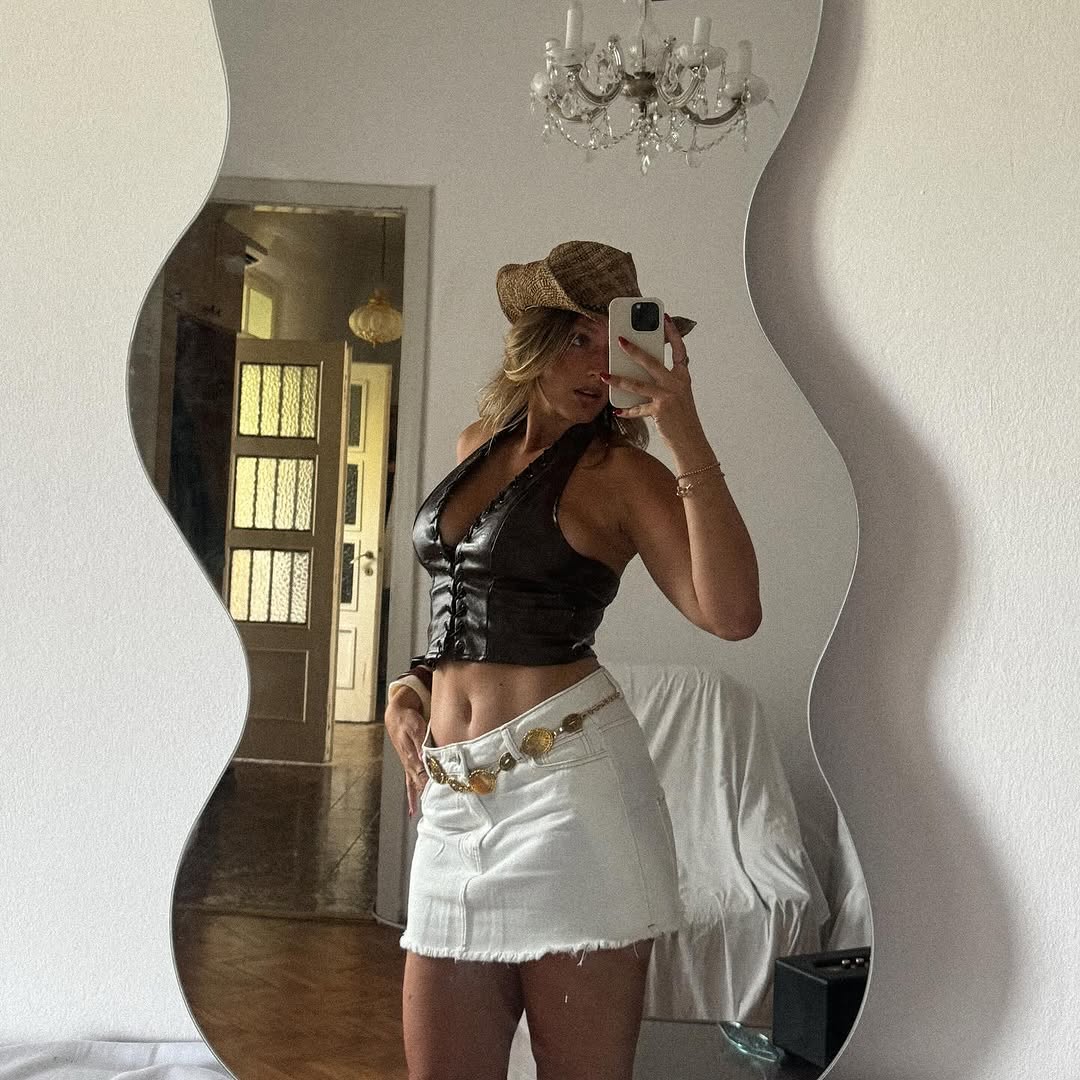 ženska pozira v ogledalo, selfi s telefonom, kavbojski stil - belo krilo in rjav top v stanovanju
