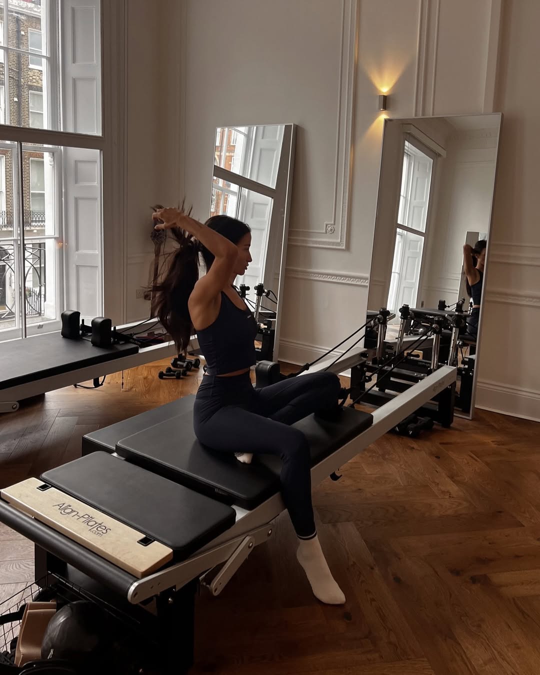 Ženska na pilates napravi, sedi, pozira, športno oblečena