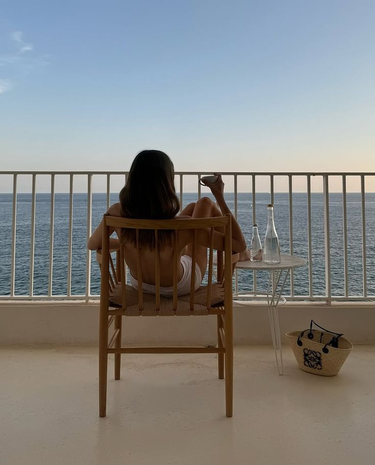 Ženska sedi na balkon, pije kavo, razgled na morje