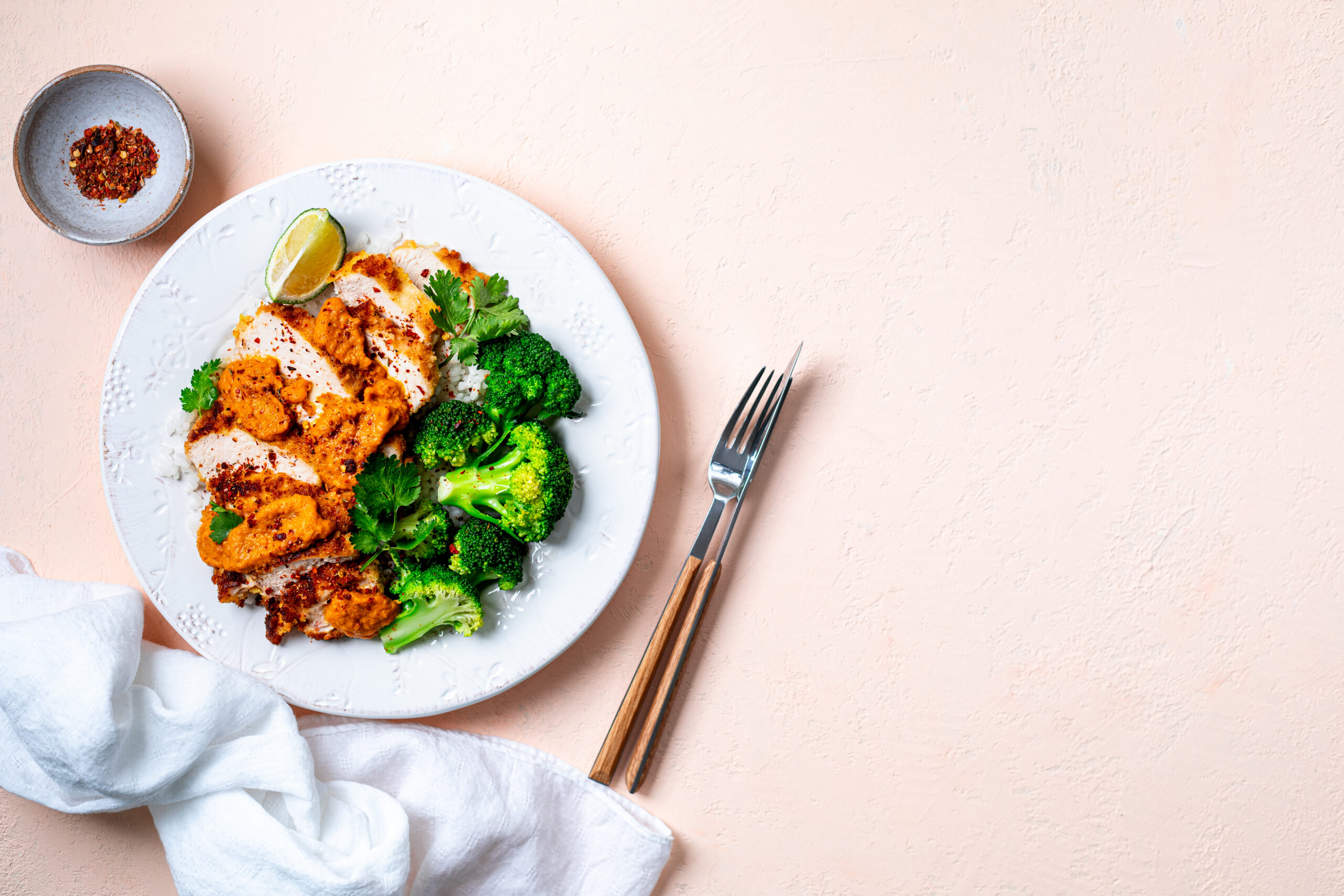 Crispy chicken cutlet with katsu sauce, with white rice and broccoli on a stone table. Top View. Peach Fuzz Background