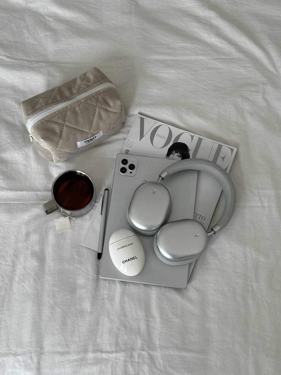 Estetska postavitev kozmetične torbice, slušalk, revije in drugih pripomočkov na postelji