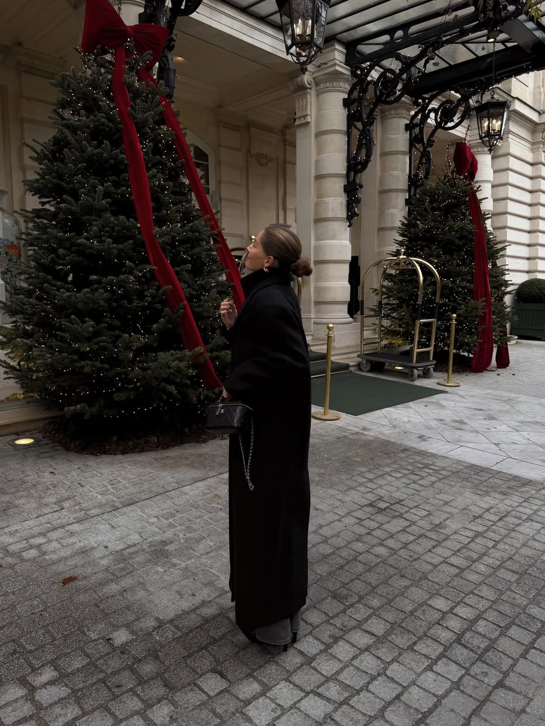 Ženska v plašču, ki gleda božično drevo