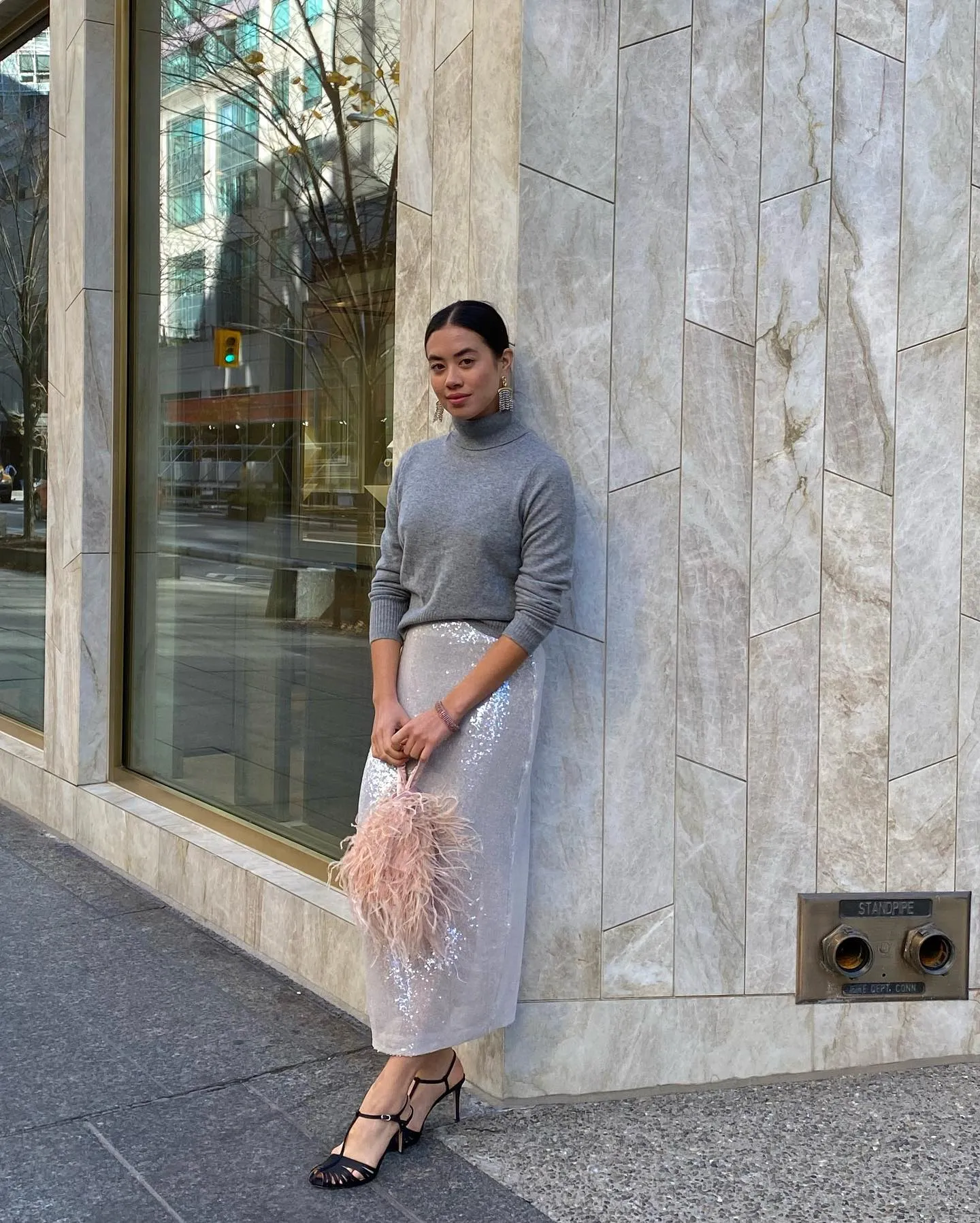 Ženska v bleščečem krilu in puloverju na ulici