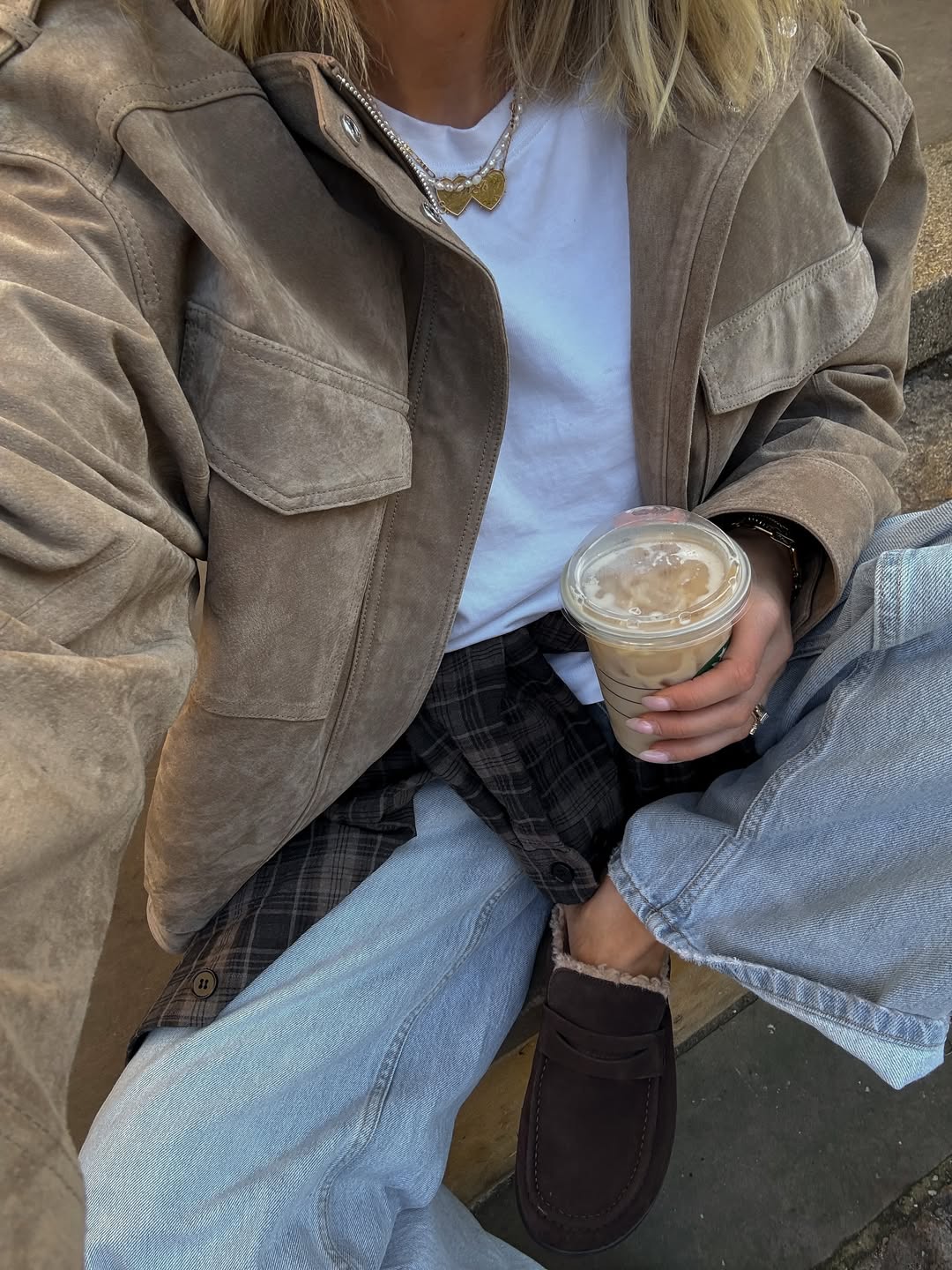 Ženska v kavbojkah, ki v rokah drži kavo